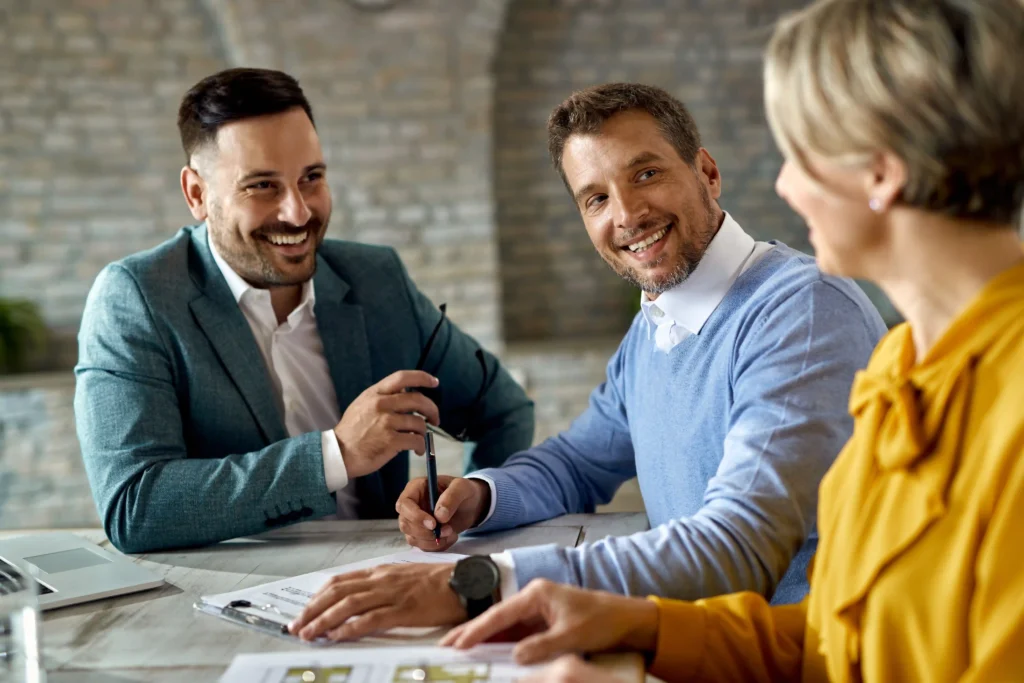happy-man-talking-his-wife-while-signing-agreement-with-insurance-agent-office