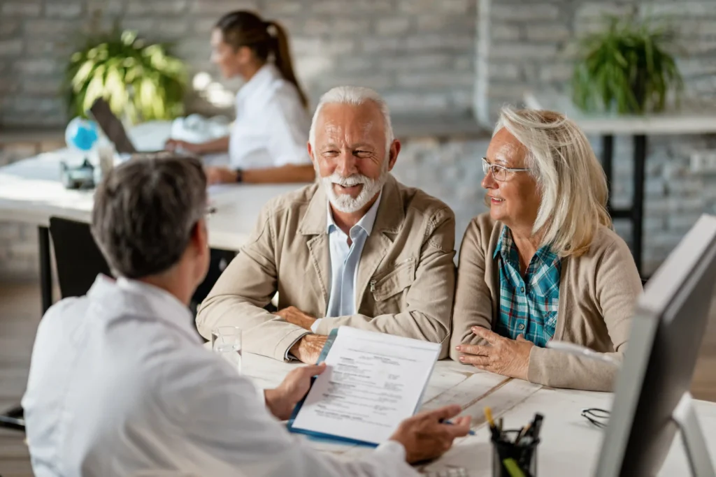 happy-senior-couple-communicating-with-doctor-about-their-health-insurance-while-going-through-paperwork